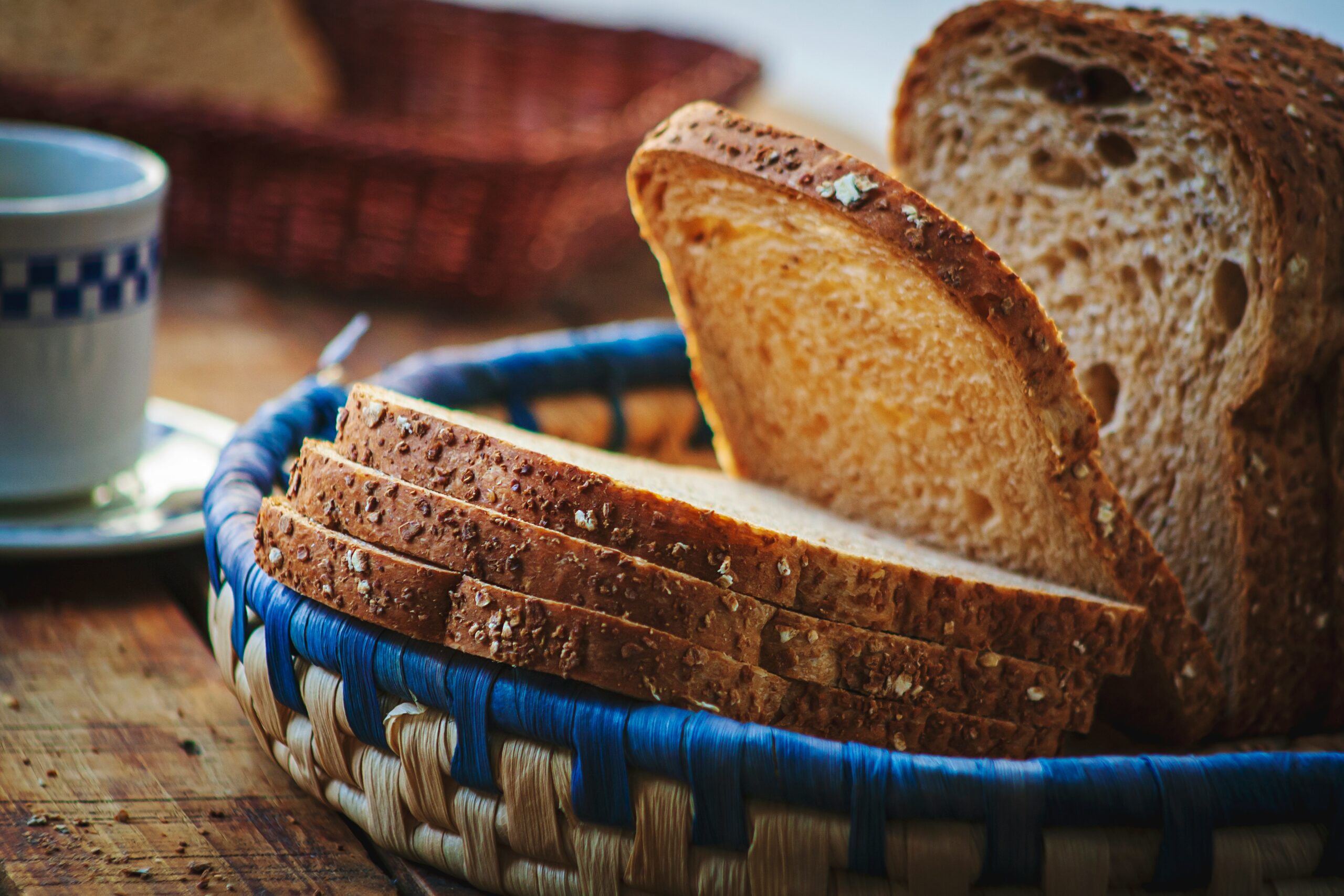 a close up of bread in a basket with a cup of coffee